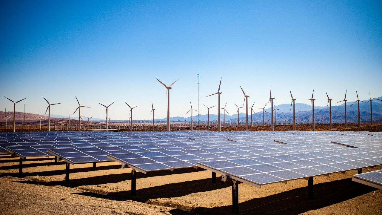 Image of a field of solar panels and windmills in the desert.